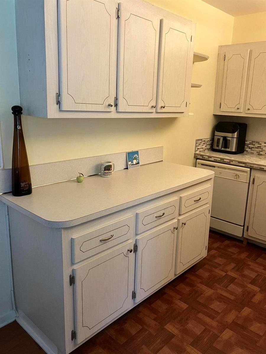 A kitchen features white cabinets, a light-colored countertop, and wood-patterned flooring — 103 Prescott E, Deerfield Beach FL 33442, DEERFIELD BEACH, FL