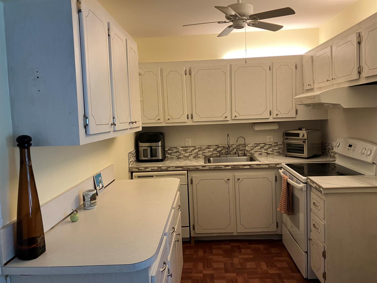 A kitchen featuring white cabinets, laminate countertops, a stainless steel sink, and a ceiling fan — 103 Prescott E, Deerfield Beach FL 33442, DEERFIELD BEACH, FL