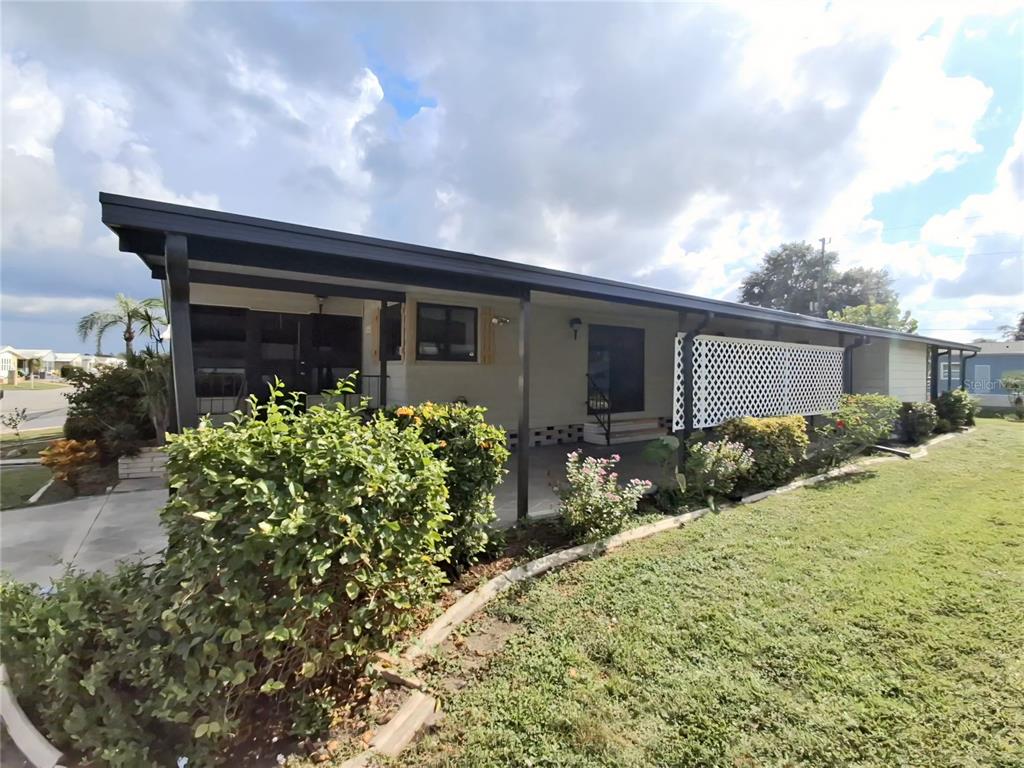 A single-story home with a covered porch, white lattice screen, and landscaped front yard — 141 RAROTONGA ROAD, NORTH PORT, FL