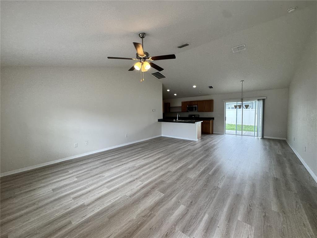 An open-concept living area features light wood-look flooring, a ceiling fan, and a kitchen island — 15492 SW 34TH COURT ROAD, OCALA, FL