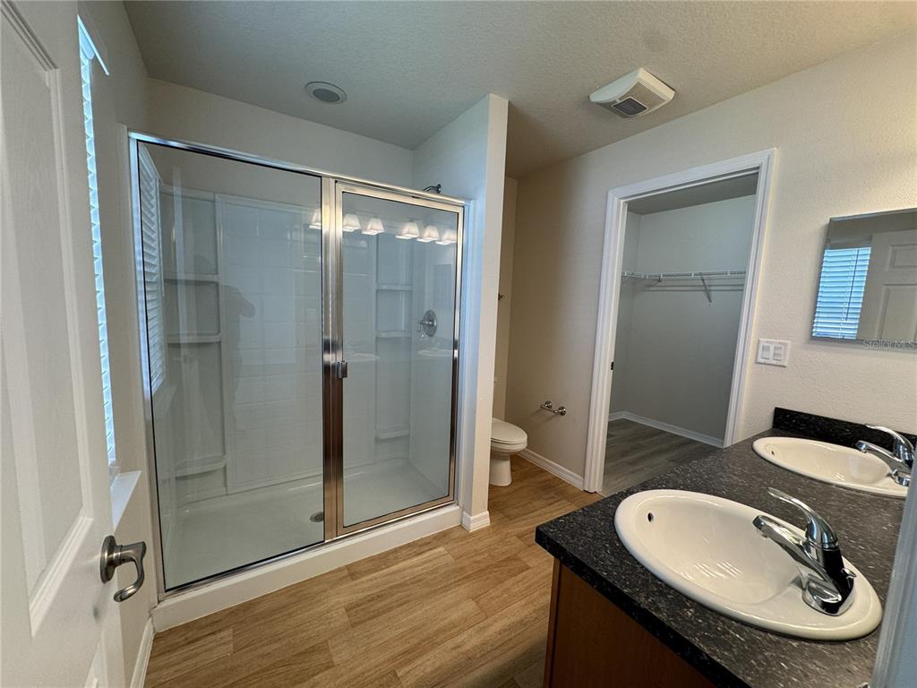 A bathroom features a glass-enclosed shower, dual vanity sinks, and wood-look flooring — 15492 SW 34TH COURT ROAD, OCALA, FL