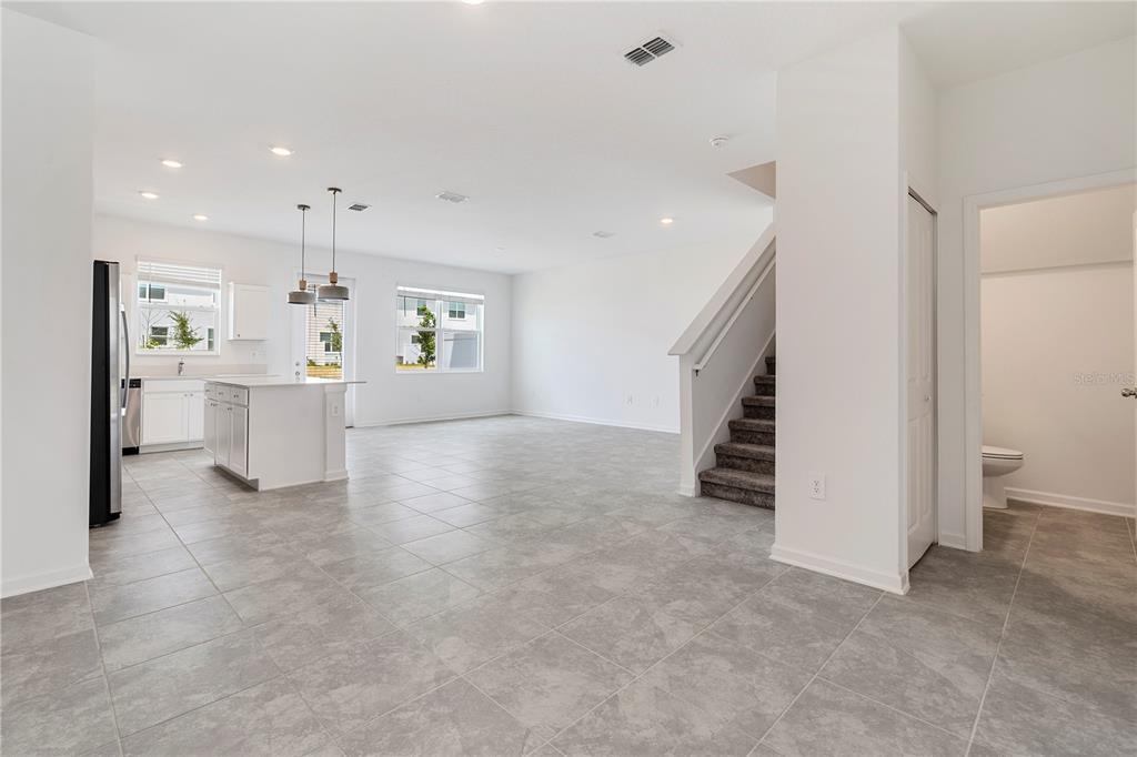 An open-concept kitchen and living area features white cabinetry, tile flooring, and a staircase — 264 NINE IRON DRIVE, DAVENPORT, FL