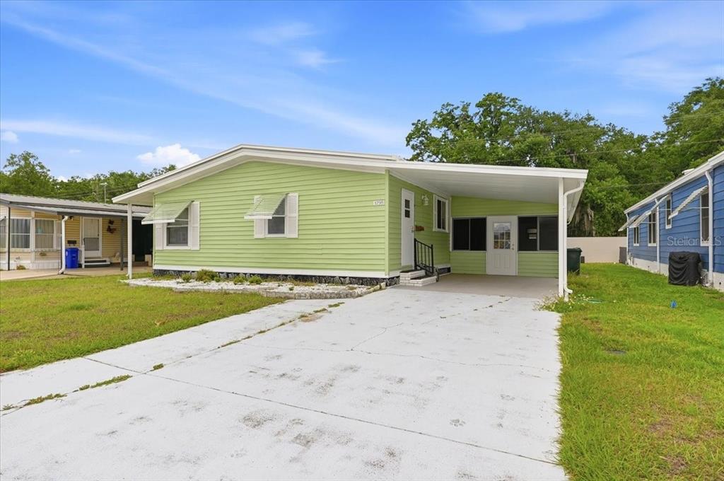 A light green mobile home features a concrete driveway, a carport, and white shutters — 1798 FOX HILL DRIVE, LAKELAND, FL