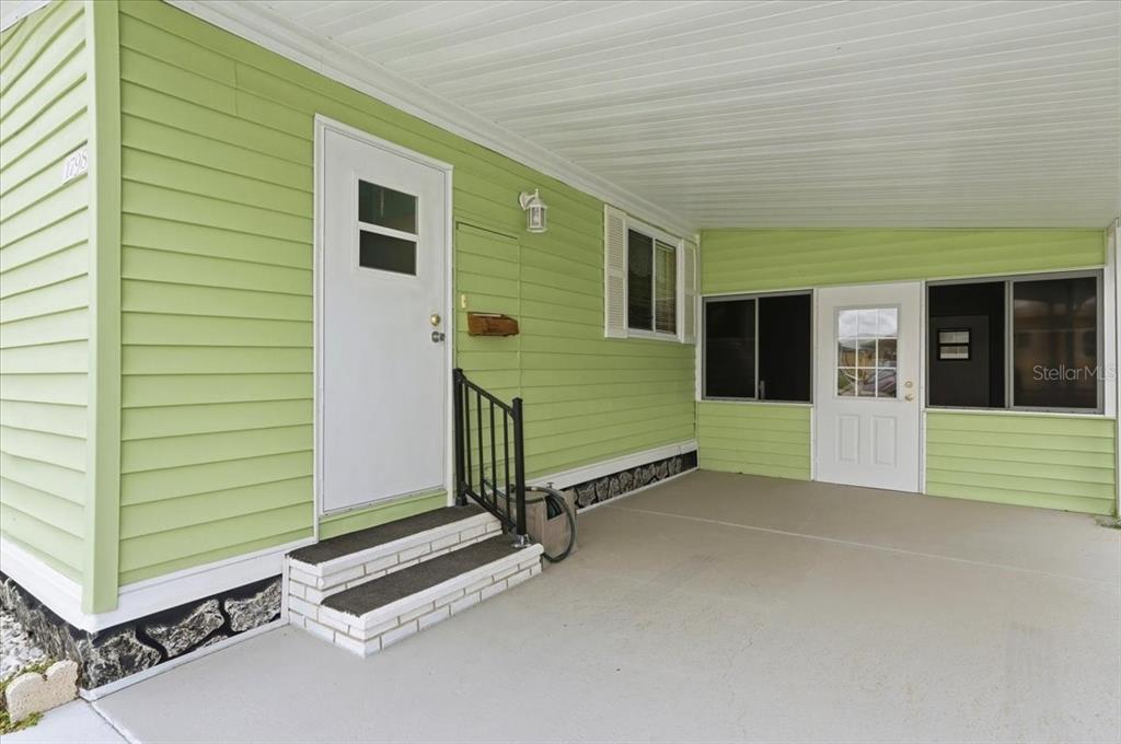 A light green house exterior features a covered carport, white doors, and concrete steps — 1798 FOX HILL DRIVE, LAKELAND, FL