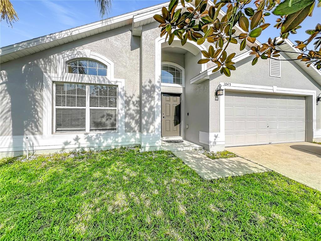 A single-story house with a gray stucco exterior, a front door, and a two-car garage — 1045 WILLOW BRANCH DRIVE, ORLANDO, FL