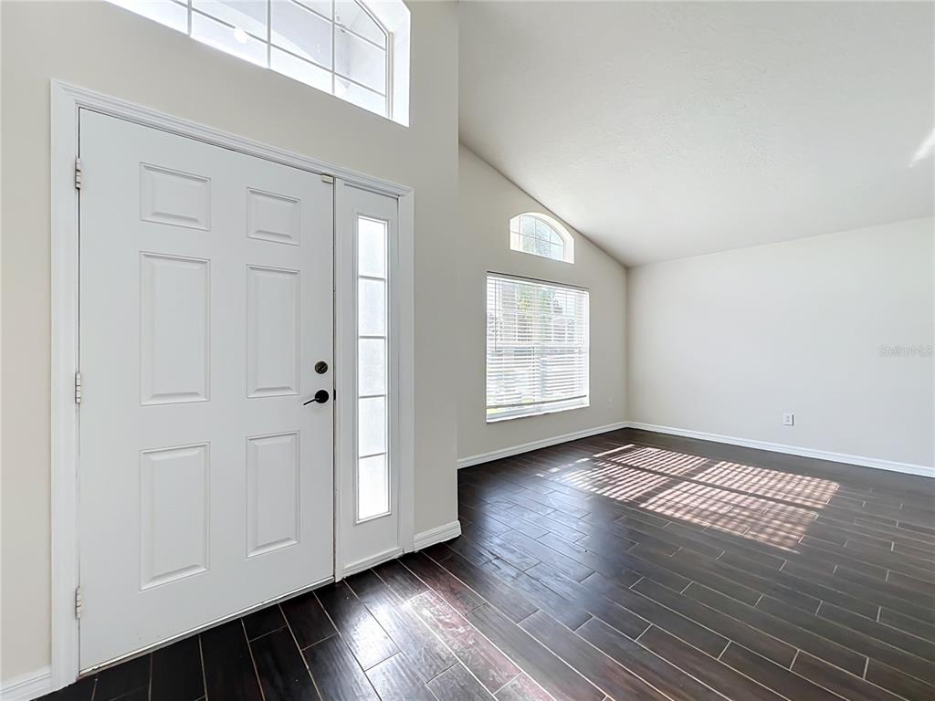 An entryway with dark wood flooring, a white front door, and high vaulted ceilings — 1045 WILLOW BRANCH DRIVE, ORLANDO, FL