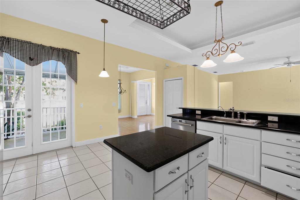 A kitchen features white cabinets, black granite countertops, a center island, and yellow walls — 10104 BALCONY STREET, NEW PORT RICHEY, FL