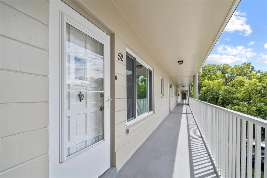 An exterior walkway with a white railing leads past apartment doors and windows — 2440 WORLD PARKWAY BOULEVARD UNIT 52, CLEARWATER, FL