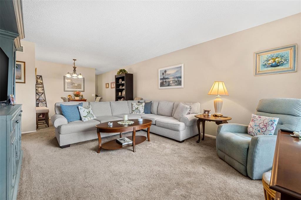 A living room features a large sectional sofa, a coffee table, and a recliner chair — 2440 WORLD PARKWAY BOULEVARD UNIT 52, CLEARWATER, FL