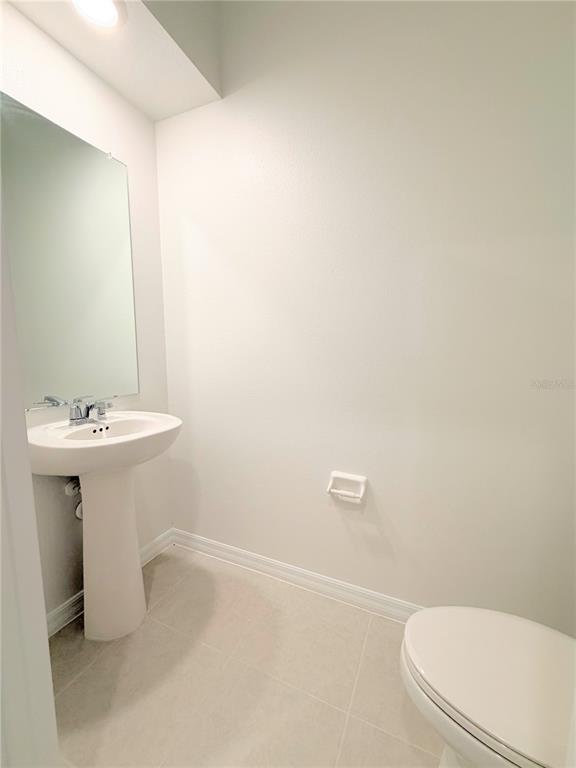 A half bathroom features a pedestal sink, a wall-mounted mirror, and light-colored tile flooring — 36162 OBSIDION LANE, ZEPHYRHILLS, FL