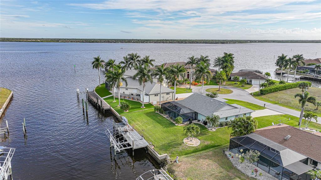 An aerial view shows waterfront houses with docks, palm trees, and screened-in pools — 3025 CURRY TERRACE, PORT CHARLOTTE, FL