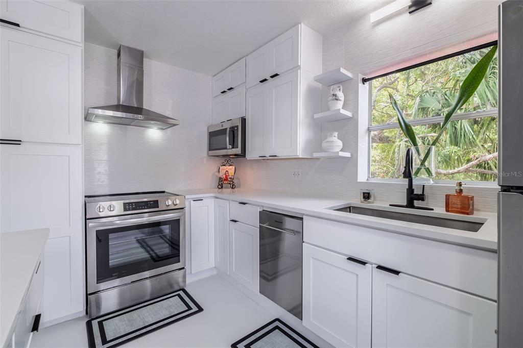 A modern kitchen features white cabinets, stainless steel appliances, a window, and a ceiling fan — 1427 ASHER LANE, ORLANDO, FL