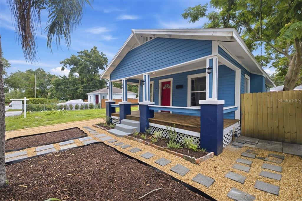 A blue bungalow with a front porch, red door, and a gravel yard with stone pavers — 3105 N 24TH STREET, TAMPA, FL