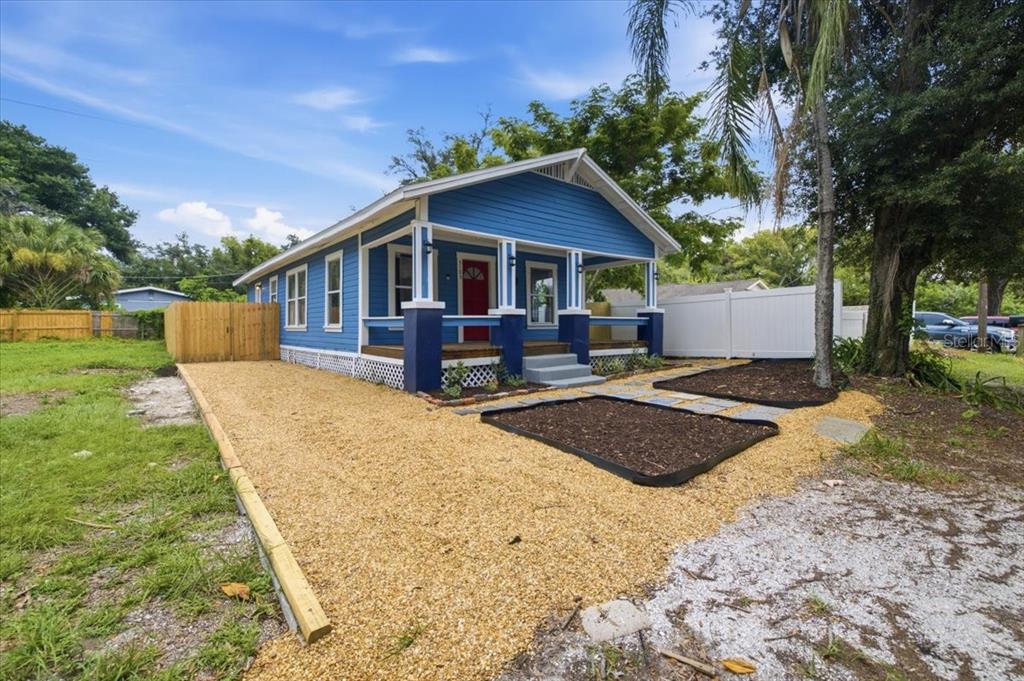 A blue house with a red front door and a gravel driveway in front — 3105 N 24TH STREET, TAMPA, FL