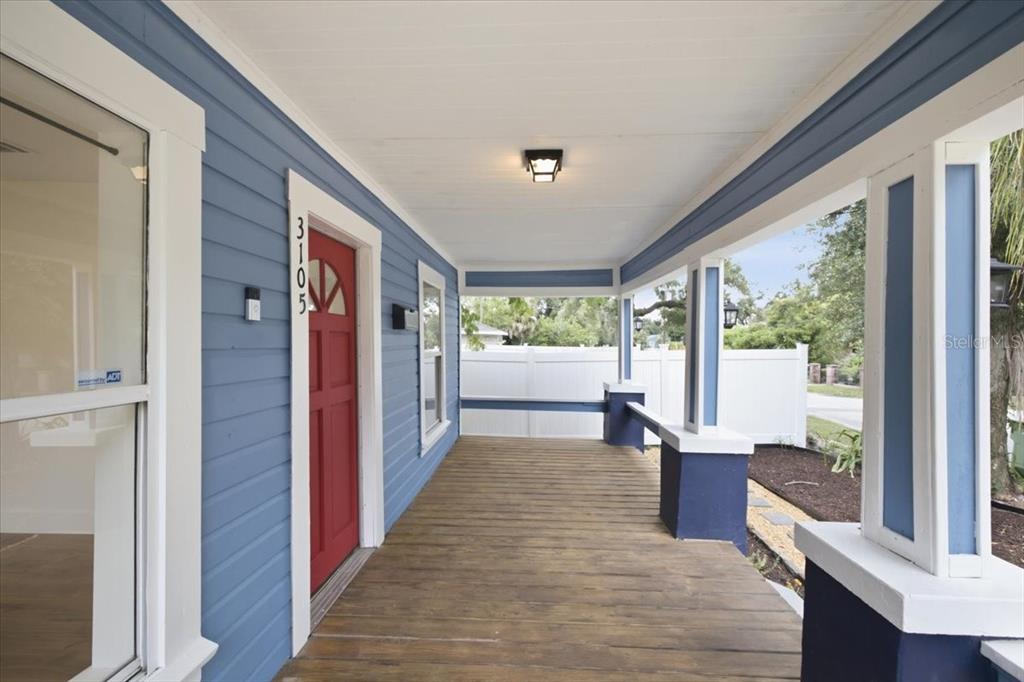 A covered front porch features blue siding, a red door, and a wooden deck floor — 3105 N 24TH STREET, TAMPA, FL
