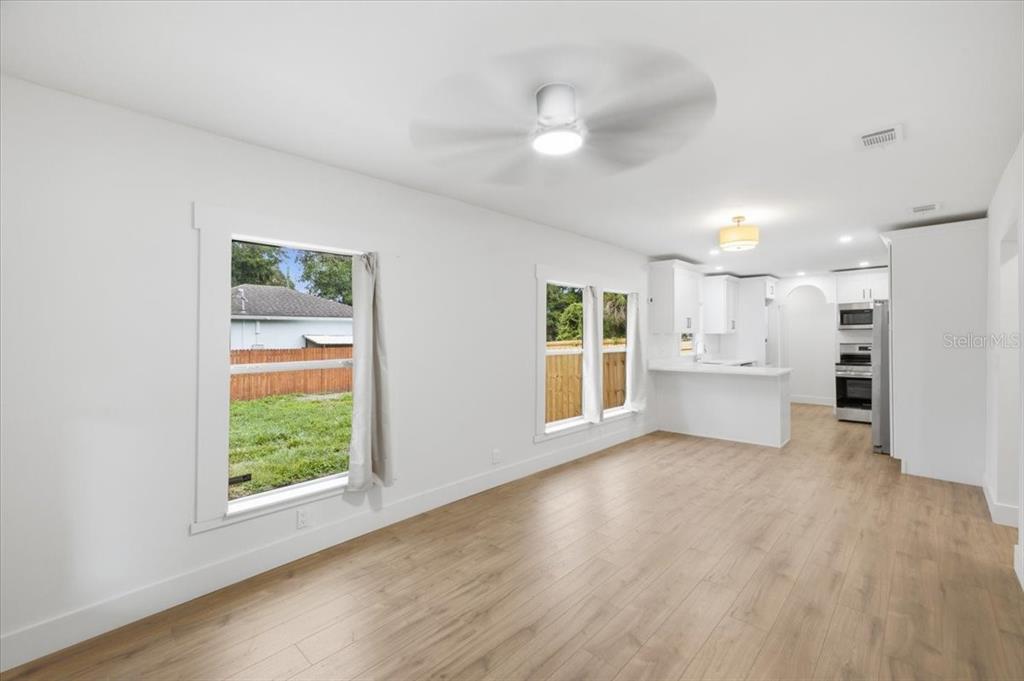 A bright living area with light wood flooring flows into an open kitchen with white cabinetry — 3105 N 24TH STREET, TAMPA, FL