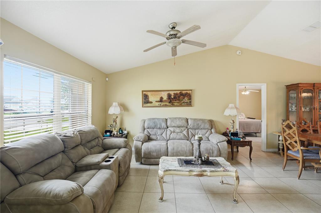 A living room features light-colored tile floors, a vaulted ceiling, and two gray reclining sofas — 642 MADRID DRIVE, KISSIMMEE, FL