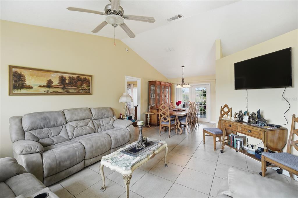 A living room with tile floors, a vaulted ceiling, and an adjacent dining area — 642 MADRID DRIVE, KISSIMMEE, FL
