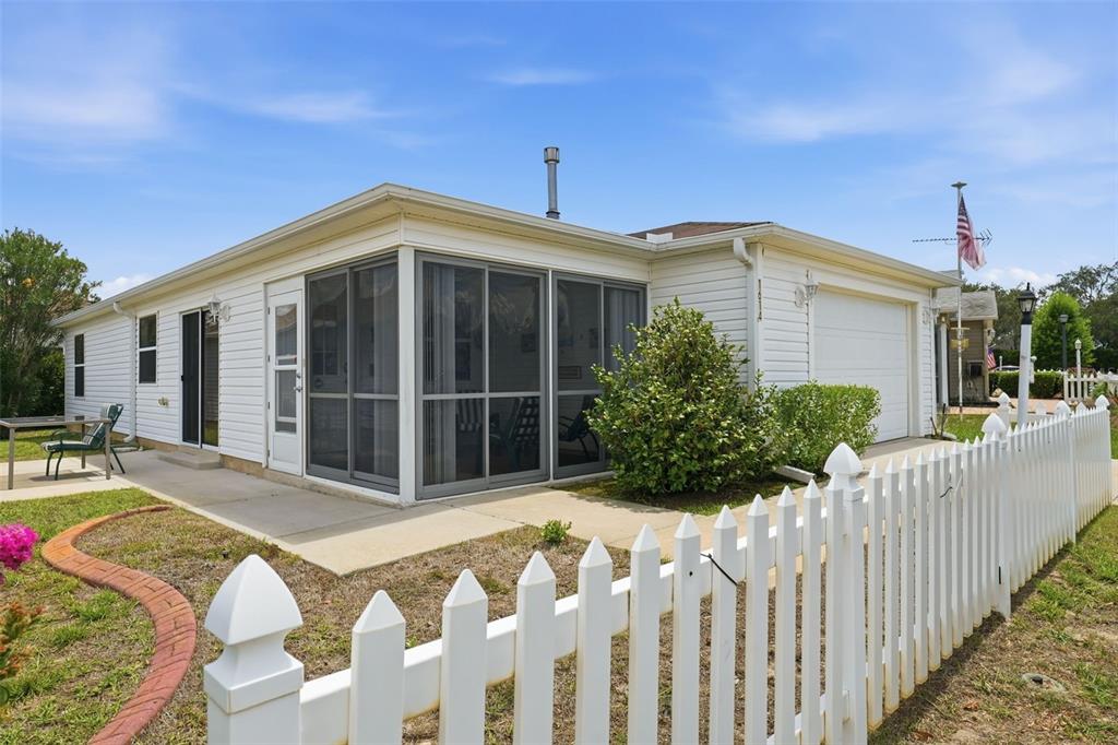 A white house with a screened-in porch, a garage, and a white picket fence — 1614 GIBBES WAY, THE VILLAGES, FL