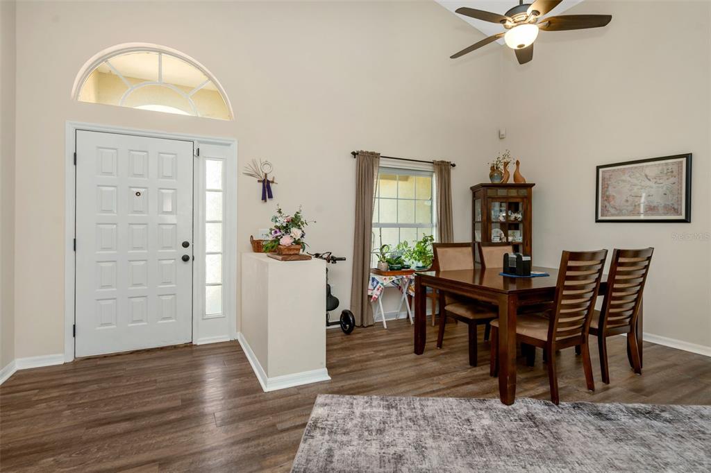 A dining area with wood flooring, a wooden table, and a front door entrance — 13853 PIMBERTON DRIVE, HUDSON, FL