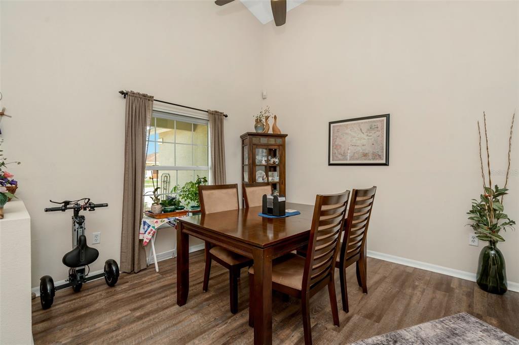 A dining room with wood-look flooring, a wooden table with four chairs, and a window — 13853 PIMBERTON DRIVE, HUDSON, FL