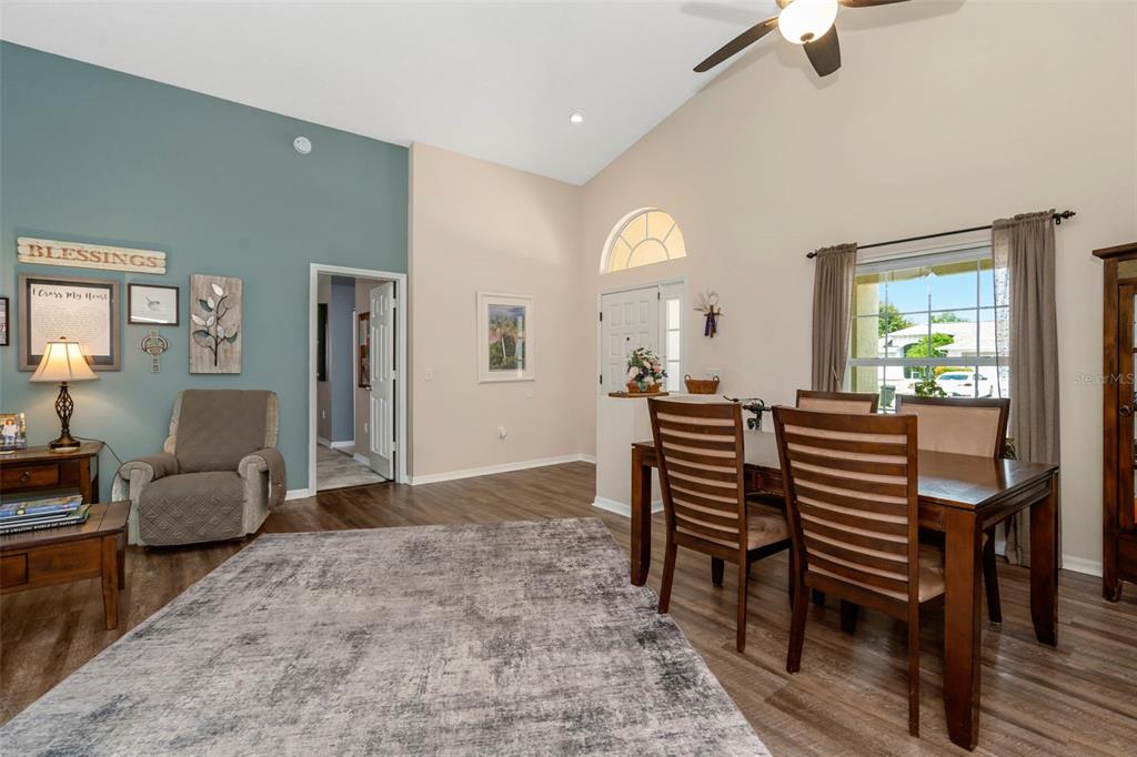 A living and dining area with vaulted ceilings, wood-look flooring, and a blue accent wall — 13853 PIMBERTON DRIVE, HUDSON, FL