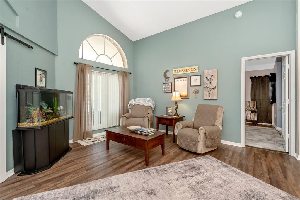 A living room features light blue walls, wood-look flooring, two armchairs, and a fish tank — 13853 PIMBERTON DRIVE, HUDSON, FL