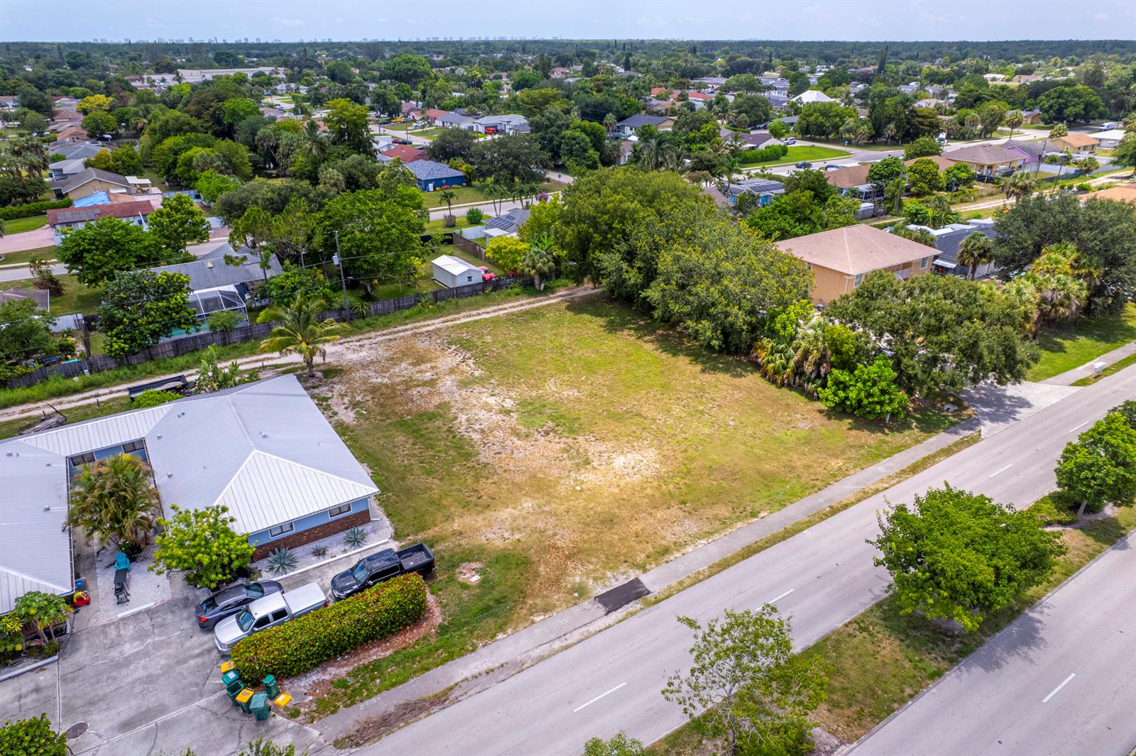 An aerial view shows a vacant grassy lot situated between a house and a road — 2171 Sunshine Boulevard, Naples FL 34116, NAPLES, FL