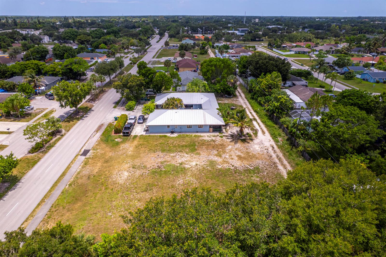An aerial view shows a single-story house with a metal roof on a large lot — 2171 Sunshine Boulevard, Naples FL 34116, NAPLES, FL