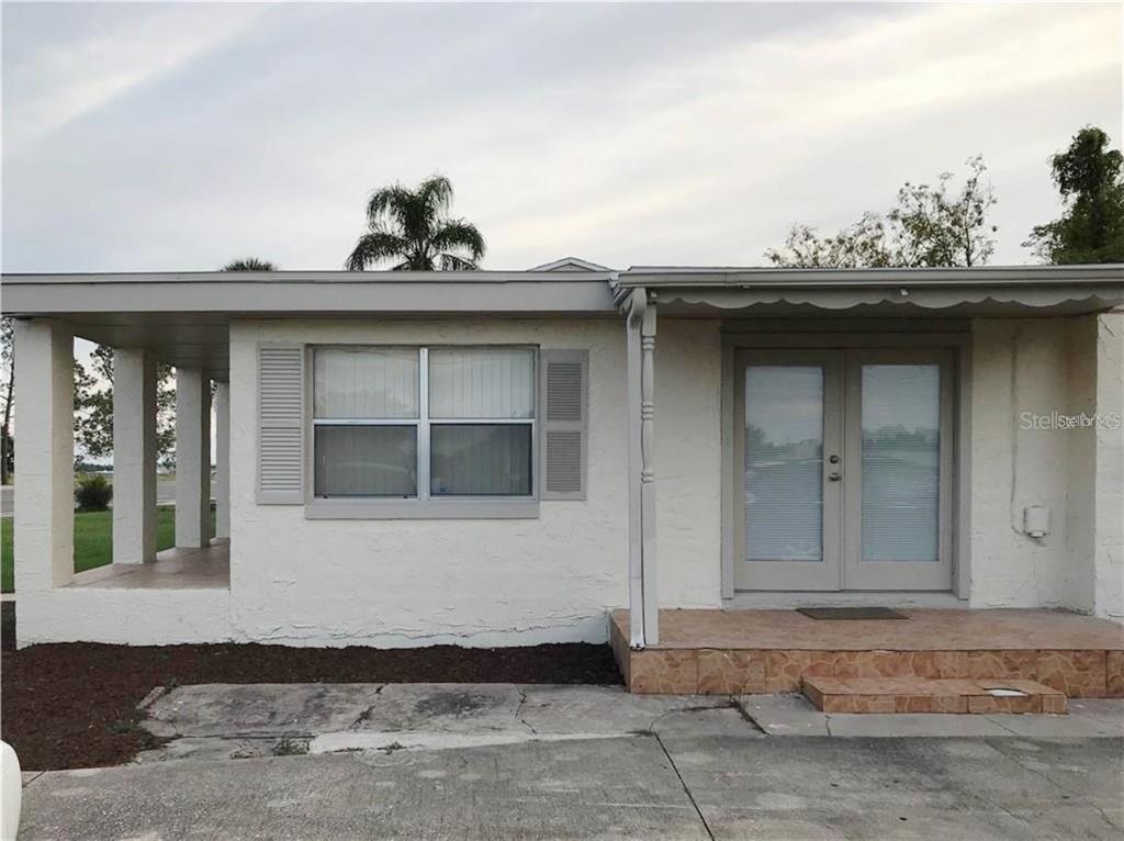The exterior of a single-story house features a covered porch, double glass doors, and stucco — 1106 N HOAGLAND BOULEVARD, KISSIMMEE, FL