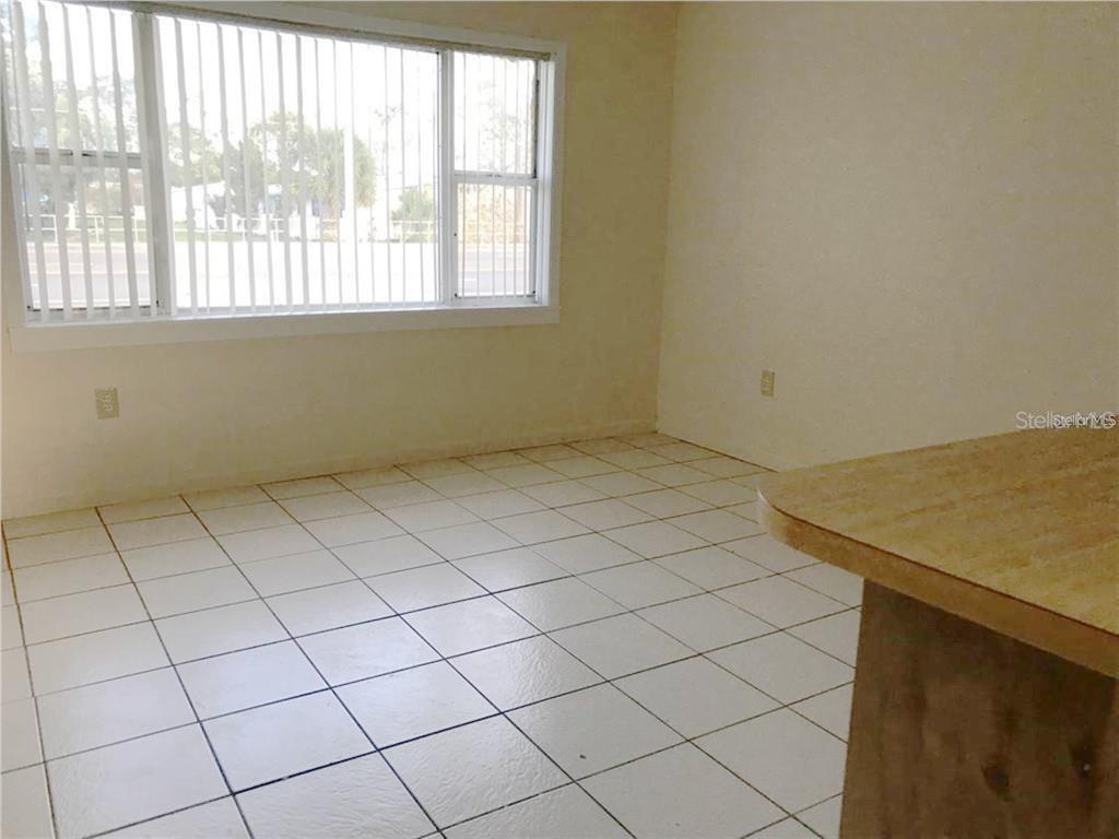 A room with white tiled floors, beige walls, and a large window with vertical blinds — 1106 N HOAGLAND BOULEVARD, KISSIMMEE, FL