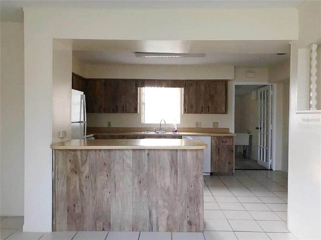 A kitchen features wood-paneled cabinetry, a breakfast bar, and white tile flooring — 1106 N HOAGLAND BOULEVARD, KISSIMMEE, FL