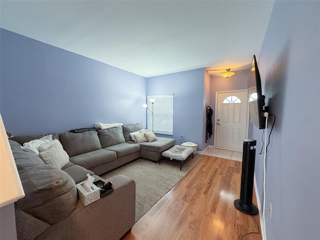 An empty room features blue walls, dark wood flooring, a window, and a front door — 7669 PLANTATION CIRCLE UNIT 7669, BRADENTON, FL