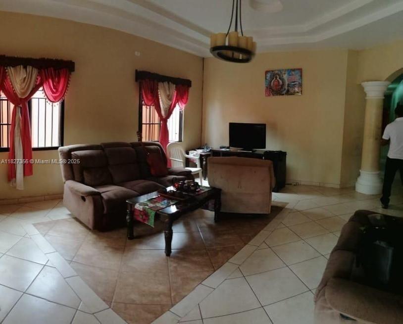 A living room features a brown sofa, a coffee table, and a television on a stand — 0000 Calle Principal Guinope, FL, FL