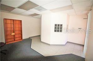 An office space features a wooden bookshelf, gray carpeting, and a tiled entryway — 3185 CONWAY ROAD UNIT D, ORLANDO, FL