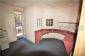 An office room features a U-shaped red desk, blue carpet, and a glass door balcony — 3185 CONWAY ROAD UNIT D, ORLANDO, FL
