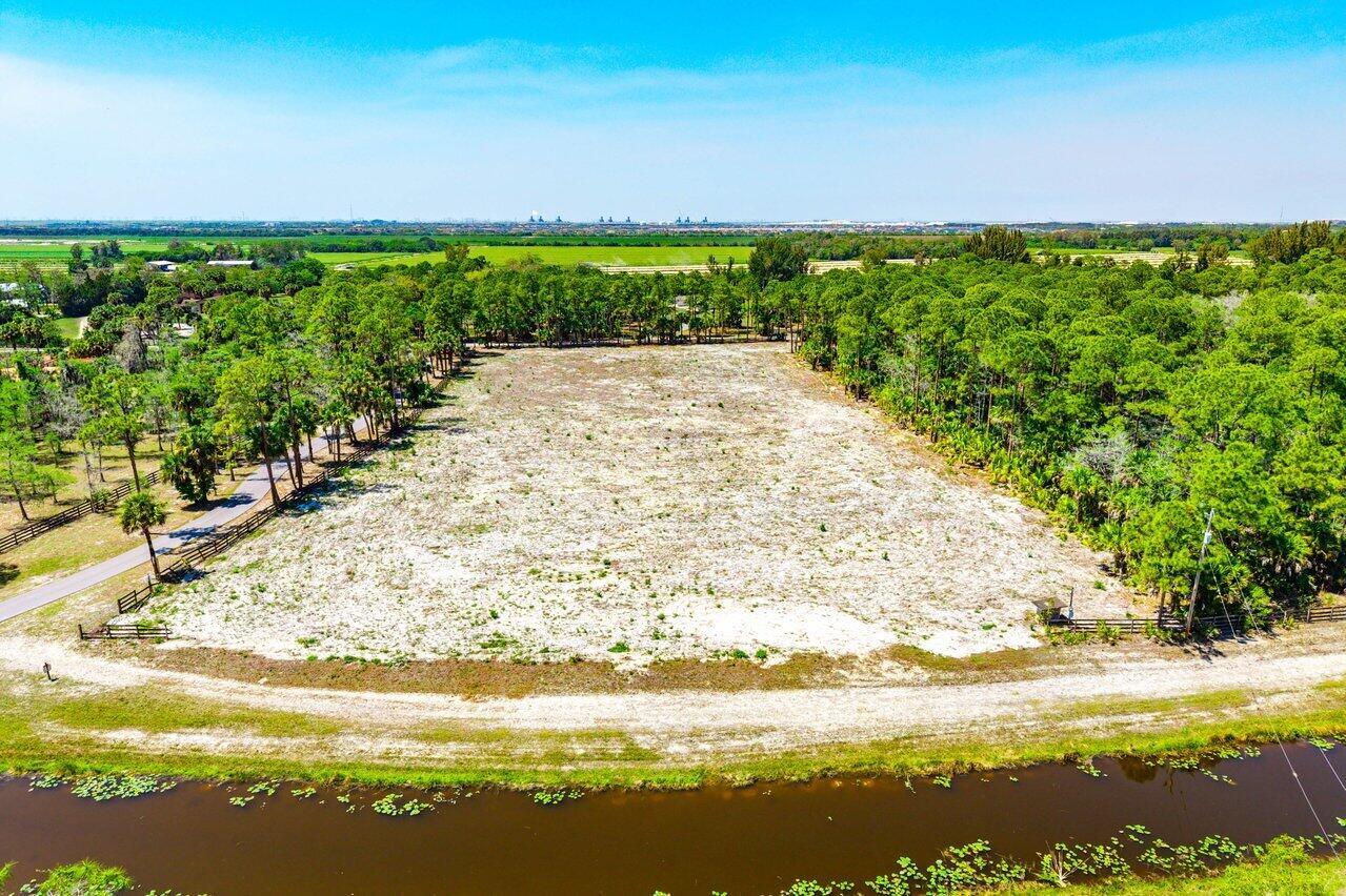 An aerial view shows a cleared, sandy rectangular lot surrounded by trees and a canal — 1278 Arabian Drive, Loxahatchee FL 33470, LOXAHATCHEE, FL