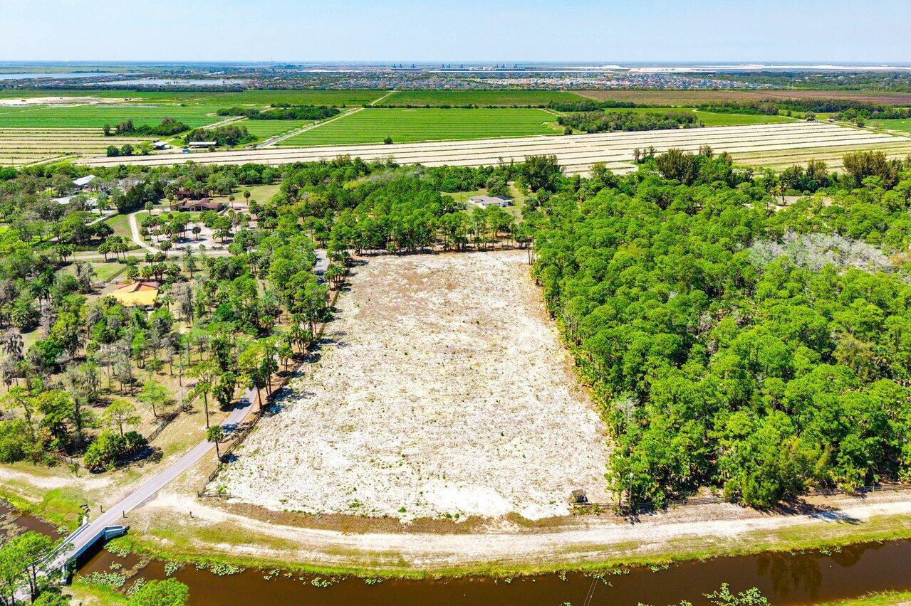 An aerial view shows a cleared, sandy rectangular lot surrounded by trees and a canal — 1278 Arabian Drive, Loxahatchee FL 33470, LOXAHATCHEE, FL