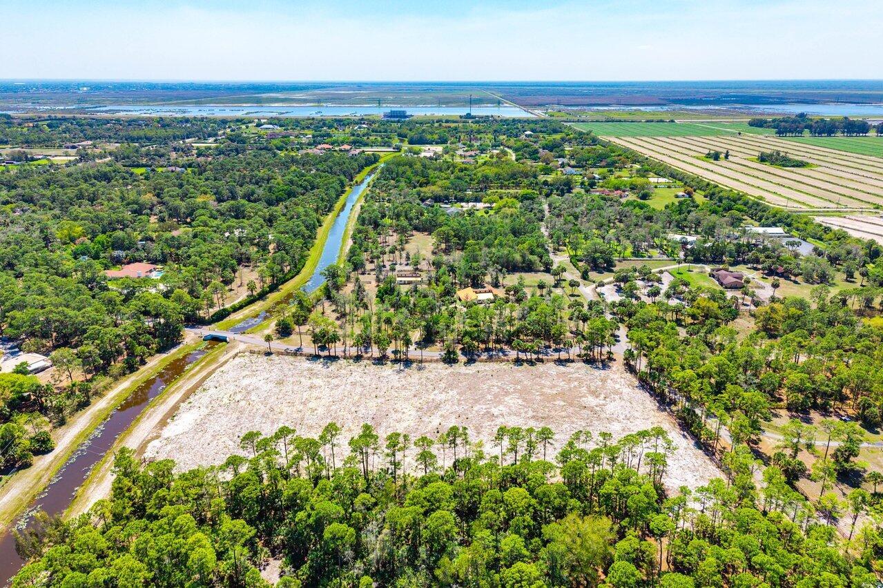 An aerial view shows a large, cleared sandy lot surrounded by dense trees and canals — 1278 Arabian Drive, Loxahatchee FL 33470, LOXAHATCHEE, FL