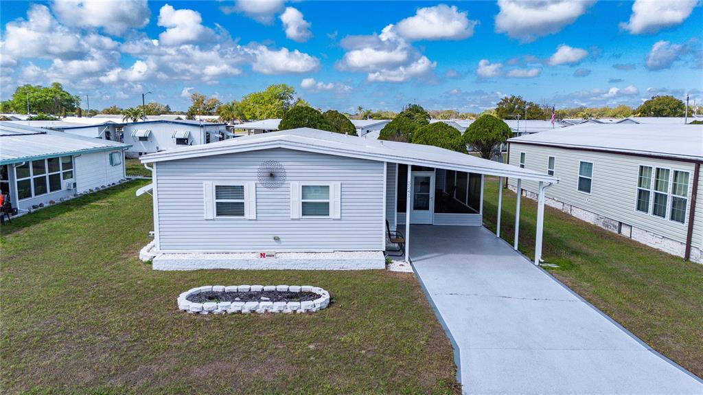 A light gray manufactured home features a concrete driveway, a carport, and a screened porch — 5541 BENTON STREET, ZEPHYRHILLS, FL