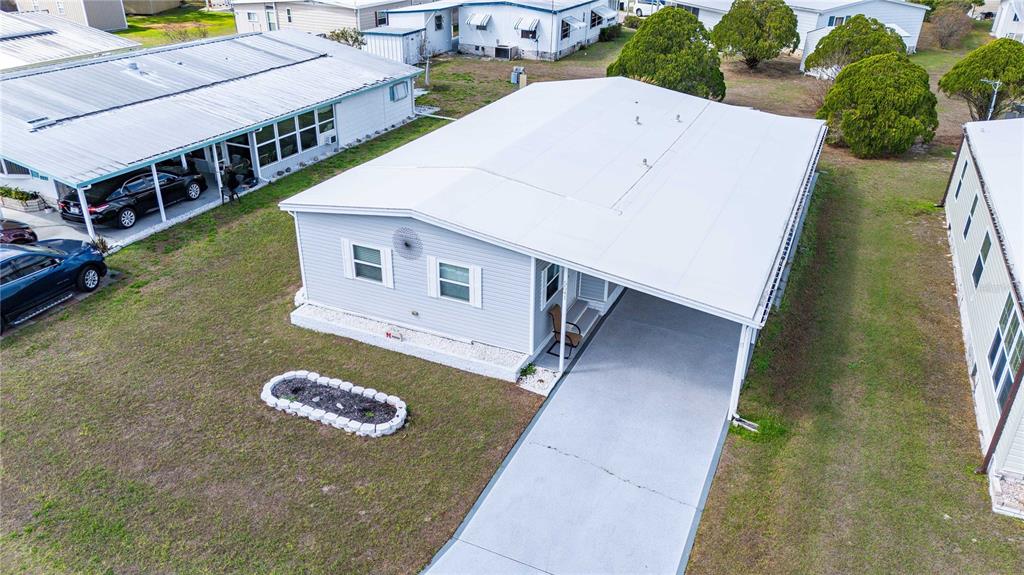 A light gray manufactured home features a concrete driveway, a carport, and a front lawn — 5541 BENTON STREET, ZEPHYRHILLS, FL
