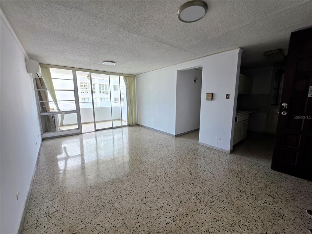 An empty living room features terrazzo flooring, white walls, and a sliding glass door balcony — 65 CALLE SANTIAGO IGLESIAS UNIT 802, SAN JUAN, PR