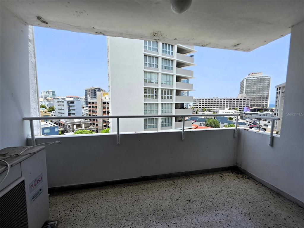 A balcony with a speckled floor, white railing, and a view of surrounding city buildings — 65 CALLE SANTIAGO IGLESIAS UNIT 802, SAN JUAN, PR
