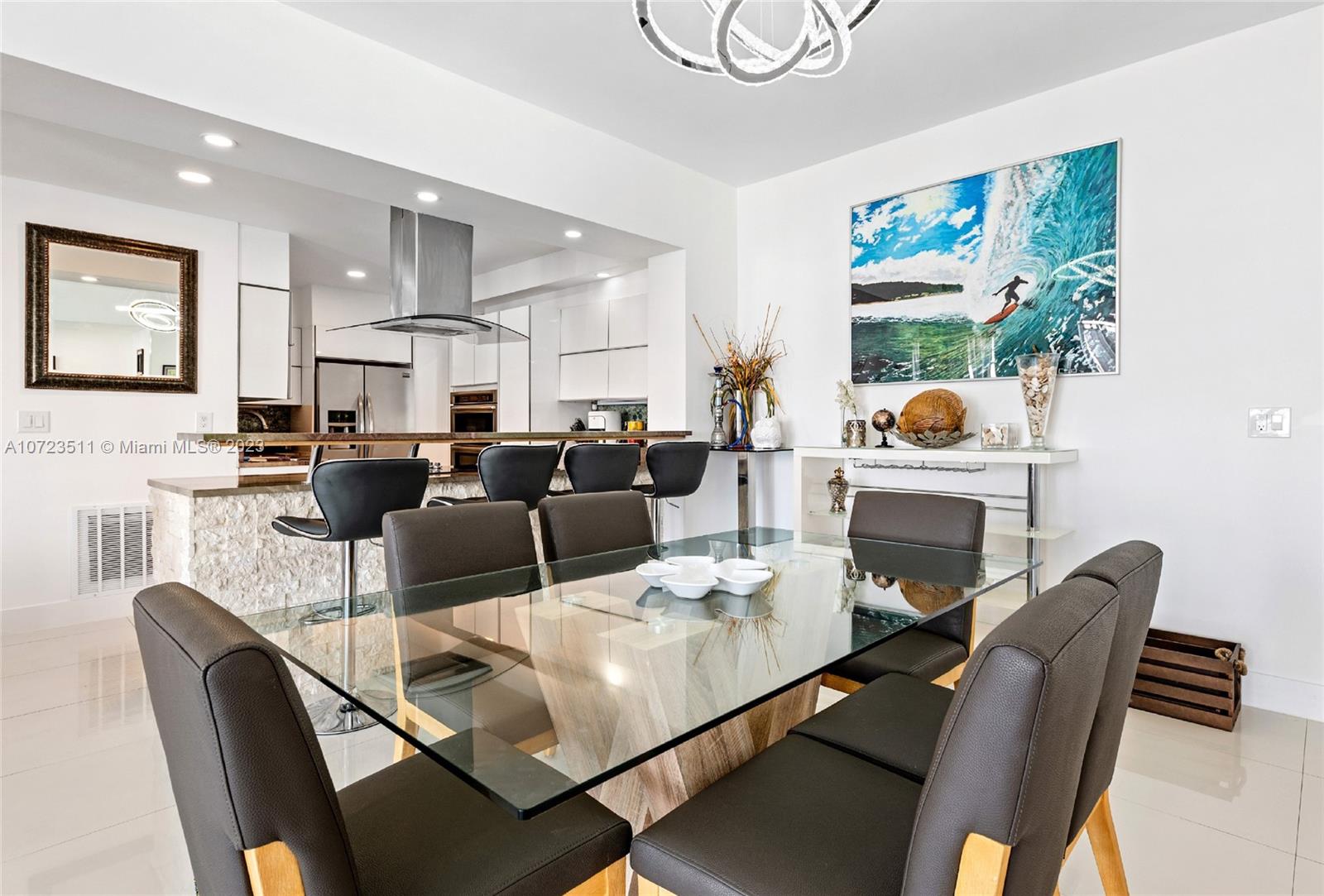 A modern dining room features a glass table, dark chairs, and an open-concept kitchen — 4001 S Ocean Dr, Hollywood FL 33019, HOLLYWOOD, FL