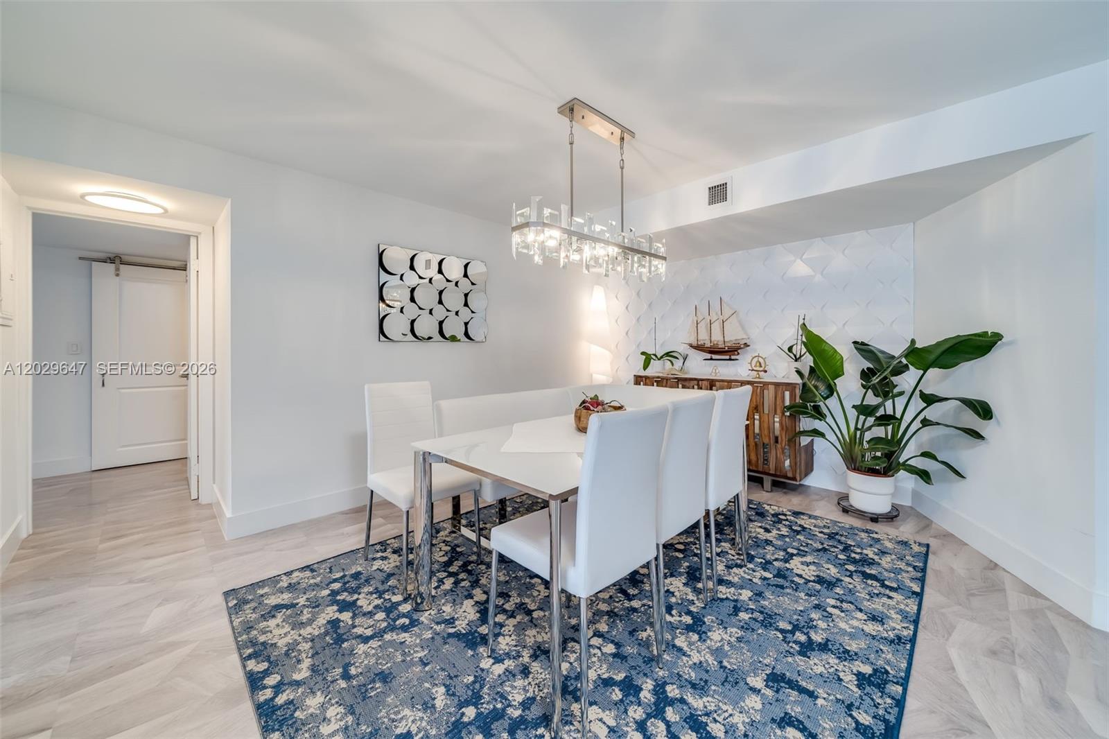 A dining room features a white table, chairs, a blue patterned rug, and textured wall — 1201 S Ocean Dr # 1105N, Hollywood FL 33019, HOLLYWOOD, FL