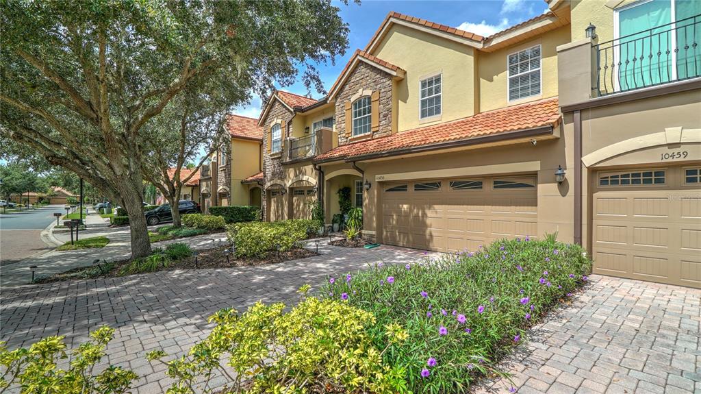 A two-story townhouse with a stone facade, tile roof, and a paved driveway — 10455 BELFRY CIRCLE, ORLANDO, FL