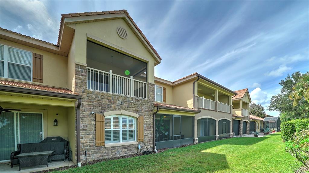 The exterior of a multi-story residential building features stone veneer, stucco walls, and screened balconies — 10455 BELFRY CIRCLE, ORLANDO, FL