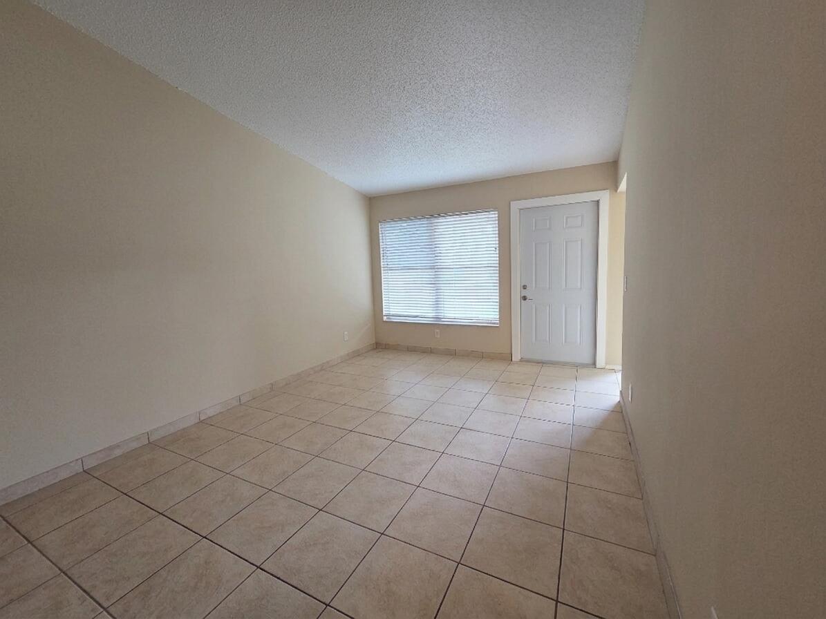 An empty room with beige walls, light-colored tile flooring, a window with blinds, and a door — 3774 Mil Race Court, FL 33463, FL