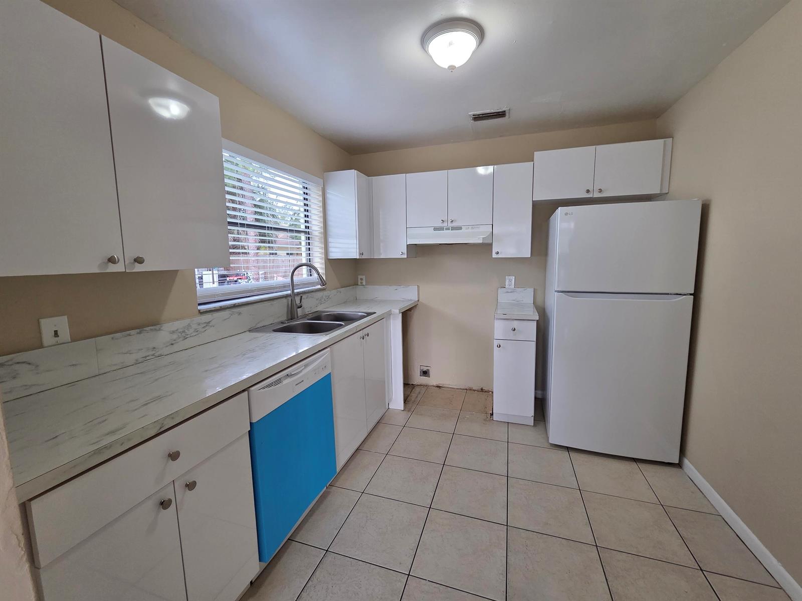 A kitchen features white cabinets, marble-patterned countertops, a blue dishwasher, and a white refrigerator — 3774 Mil Race Court, FL 33463, FL