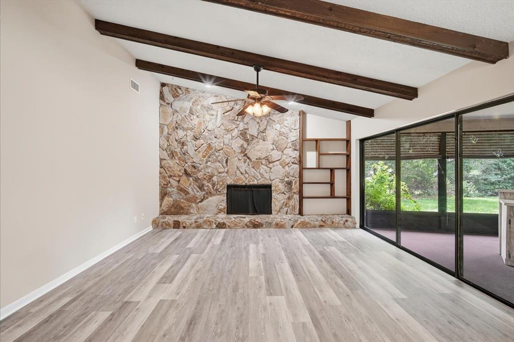 A living room features a stone fireplace, wood ceiling beams, and sliding glass doors — 1405 LAUREL COURT, PLANT CITY, FL